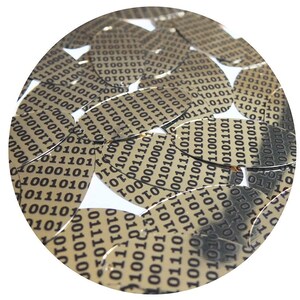 Puede incluir: Primer plano de un grupo de lentejuelas doradas con un patrón de código binario negro. Las lentejuelas están dispuestas en un patrón circular.