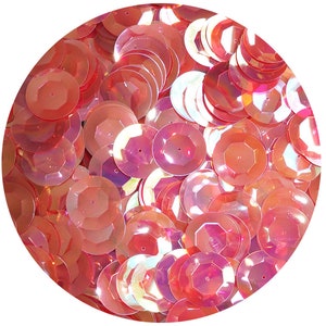 May include: A collection of iridescent, coral-colored sequins. The sequins are round with a faceted design, catching the light and creating a shimmering effect. They are scattered closely together, filling a circular space against a white background.