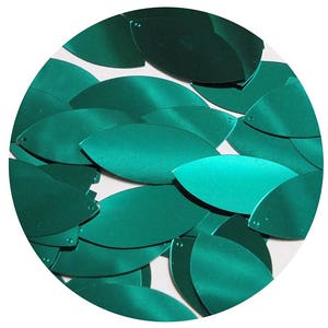 May include: A close-up of teal green leaf-shaped sequins. The sequins are arranged in a circular pattern and have a metallic sheen.