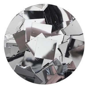 May include: A pile of silver square sequins. The sequins are shiny and reflective.