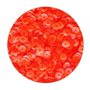 May include: A close-up of a large quantity of bright orange sequins. The sequins are arranged in a circular pattern, creating a shimmering effect.