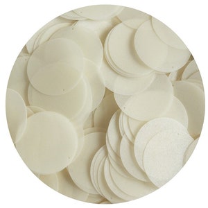 Pode incluir: Um monte de lantejoulas redondas de cor branco-queimado. As lantejoulas são feitas de um material brilhante e têm um furo no centro.