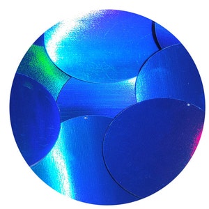 May include: A close-up of iridescent blue sequins arranged in a circular pattern. The sequins are overlapping and create a shimmering effect.
