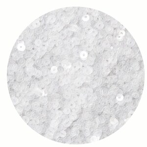 May include: A close-up of a white sequin fabric. The sequins are small and round, and they are arranged in a close-packed pattern.