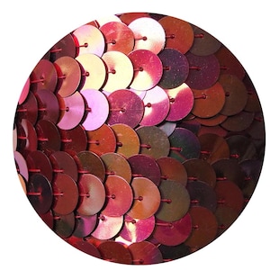 May include: Close-up of a sheet of iridescent red sequins. The sequins are sewn together in a circular pattern.