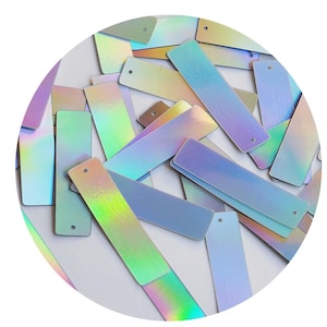 May include: A collection of iridescent rectangular sequins with a hole in the top. The sequins are various shades of blue, green, and purple.