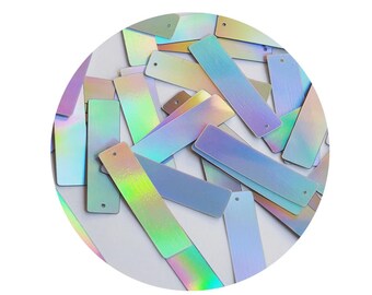 Könnte beinhalten: Eine Sammlung von regenbogenfarbenen rechteckigen Pailletten mit einem Loch oben. Die Pailletten sind in verschiedenen Blautönen, Grüntönen und Violetttönen gehalten.