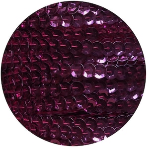 Puede incluir: Primer plano de una tela cubierta de pequeñas lentejuelas redondas e iridiscentes de color morado.