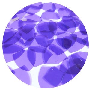 Può includere: Primo piano di un mucchio di paillettes iridescenti viola. Le paillettes sono sparse su una superficie bianca.