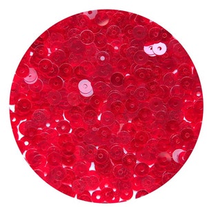 May include: A close-up of a pile of red sequins. The sequins are small and round, with a hole in the center. They are arranged in a random pattern.