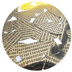 Puede incluir: Primer plano de una disposición circular de piezas metálicas doradas, cada una con un patrón repetitivo de código binario negro, 1 y 0.