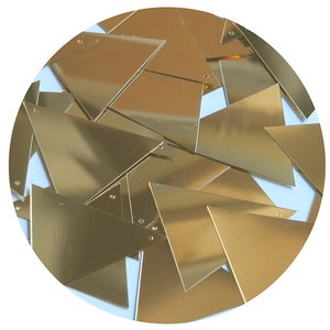May include: A collection of shiny, gold-colored triangle-shaped pieces. Each piece has a small hole near one of the corners. The pieces are scattered, overlapping each other, and appear to be made of a metallic material.