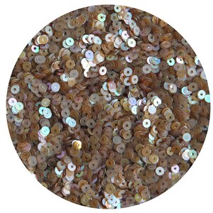 May include: A close-up image of a pile of iridescent gold sequins. The sequins are round and have a hole in the center. They are perfect for crafting and decorating.