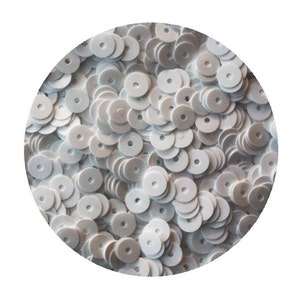 May include: A close-up image of a large quantity of white round sequins. The sequins are arranged in a circular pattern, creating a visually appealing and textured surface.