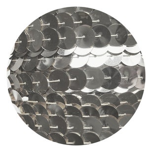 Può includere: Paillettes argentate disposte in un motivo circolare, creando una superficie scintillante e riflettente.