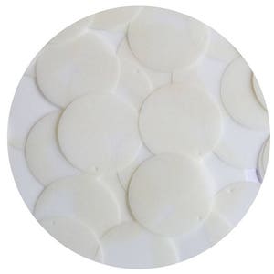 Pode incluir: Uma disposição circular de lantejoulas planas, redondas e esbranquiçadas. Cada lantejoula tem um pequeno orifício perto da borda. As lantejoulas se sobrepõem, criando uma superfície texturizada. O fundo é branco.