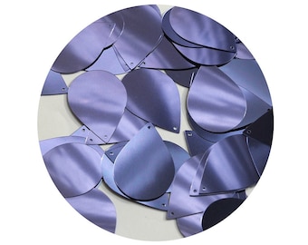 May include: A pile of iridescent purple teardrop-shaped sequins. The sequins are made of a shiny, metallic material and have a slightly textured surface.