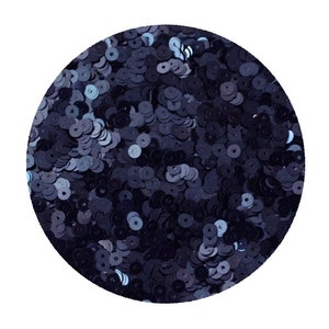 May include: A close-up of a pile of dark blue sequins. The sequins are small and round, and they are arranged in a random pattern.