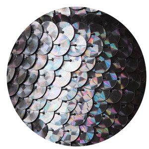 Può includere: Primo piano di paillettes nere iridescenti disposte in un motivo circolare. Le paillettes sono piccole e rotonde, con un centro leggermente rialzato. L'effetto generale è quello di un luccichio e di uno scintillio.