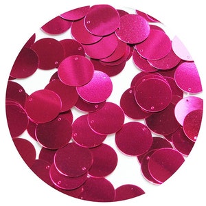 May include: A close-up of a pile of bright pink round sequins. The sequins are shiny and have a metallic finish.