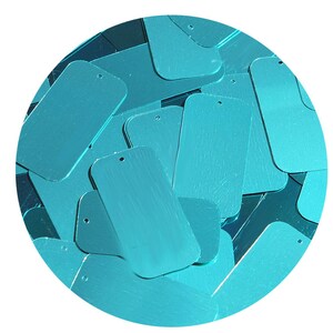 May include: A close-up of a pile of turquoise blue rectangular sequins. The sequins have a metallic sheen and are perfect for crafting and decorating.