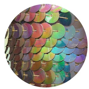 Puede incluir: Primer plano de lentejuelas iridiscentes dispuestas en un patrón circular. Las lentejuelas son de varios colores, incluyendo morado, azul, verde y dorado.