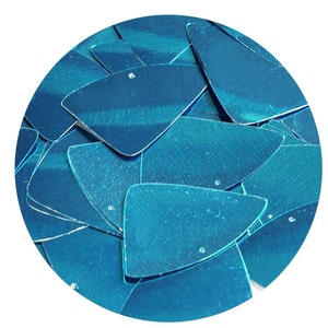 May include: A close-up of a pile of turquoise blue iridescent sequins. The sequins are shaped like triangles with rounded corners.