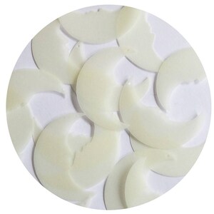 Pode incluir: Uma coleção de objetos em forma de crescente, esbranquiçados, dispostos sobre um fundo circular branco. Os objetos têm uma textura lisa e ligeiramente brilhante e parecem ser feitos de um material sólido. A disposição é dispersa, com algumas sobreposições.