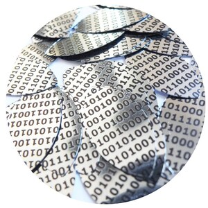 Puede incluir: Primer plano de una pila de piezas circulares rotas de color plateado con un patrón de código binario negro impreso en ellas.