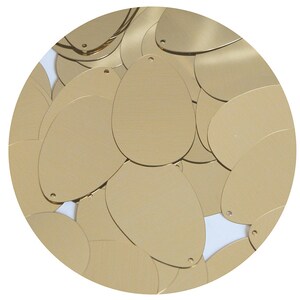 May include: A pile of gold oval sequins. The sequins are shiny and have a metallic finish.
