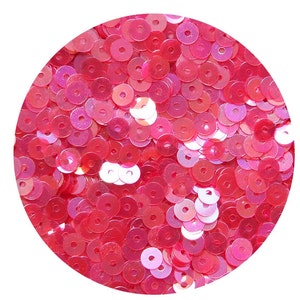 May include: A close-up of a pile of pink iridescent sequins. The sequins are round with a hole in the centre.