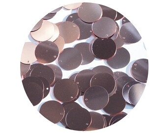 May include: A close-up of a pile of rose gold round sequins. The sequins are shiny and have a metallic finish.