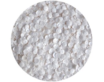 May include: A close-up view of a large quantity of white round sequins. The sequins have a slightly iridescent finish.