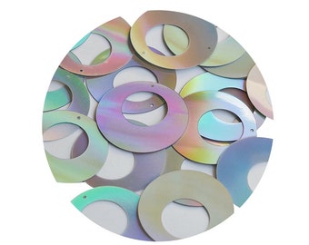 May include: A pile of iridescent, round sequins with a hole in the centre. The sequins are various shades of blue, green, and purple.