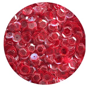 Puede incluir: Una imagen de primer plano de un montón de lentejuelas rojas iridiscentes. Las lentejuelas son redondas con un diseño ligeramente facetado.