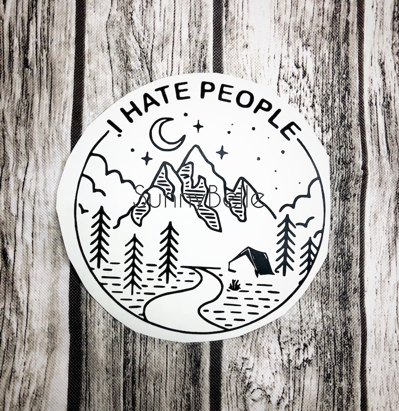 May include: A white sticker with a black line drawing of a mountain scene. The design includes mountains, trees, a crescent moon, stars, and a tent. The text "I HATE PEOPLE" is written around the top edge of the sticker.