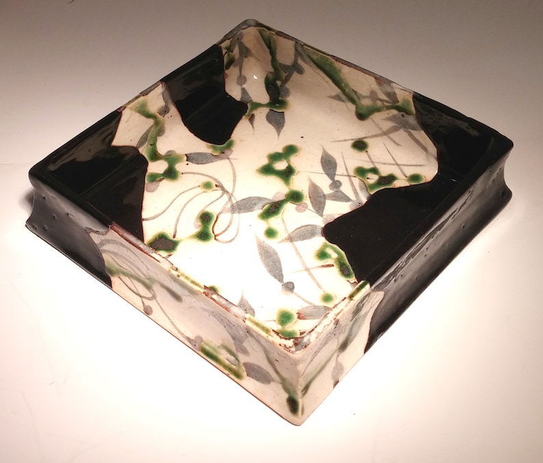 Oribe dish Japanese stoneware green and black pattern of grey green leaves and line shape of diamonds on a beige background