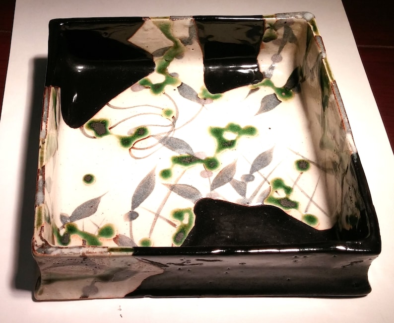 Oribe dish Japanese stoneware green and black pattern of grey green leaves and line shape of diamonds on a beige background