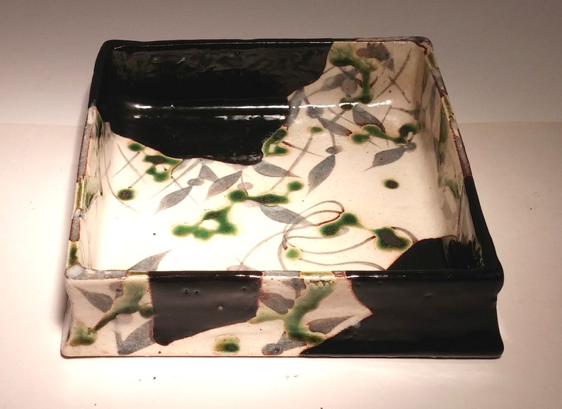 Oribe dish Japanese stoneware green and black pattern of grey green leaves and line shape of diamonds on a beige background