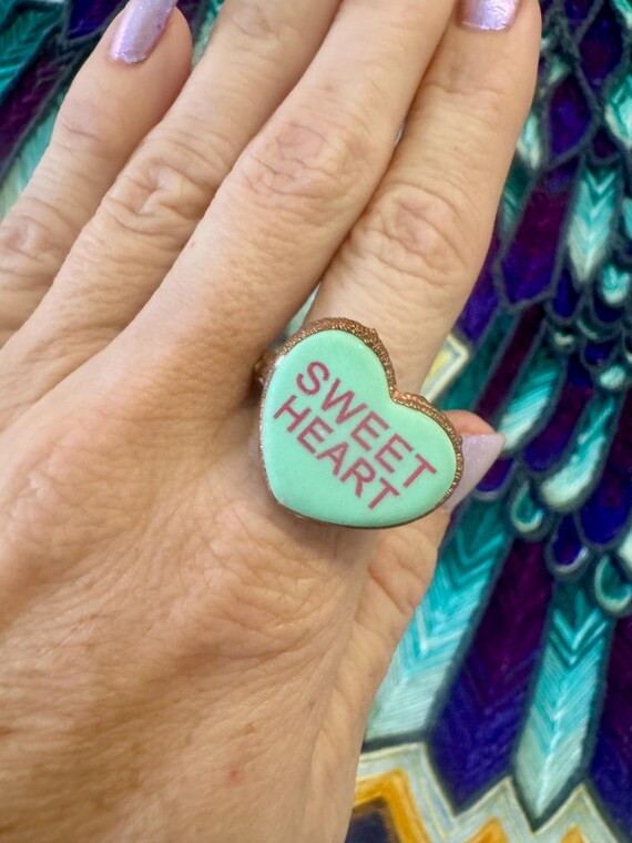A real candy conversation heart recreated in electroformed copper — wearable nostalgia turned into surprisingly striking jewelry.