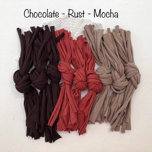 May include: Three knotted ropes in chocolate, rust, and mocha colors. The ropes are made of fabric and have frayed ends.