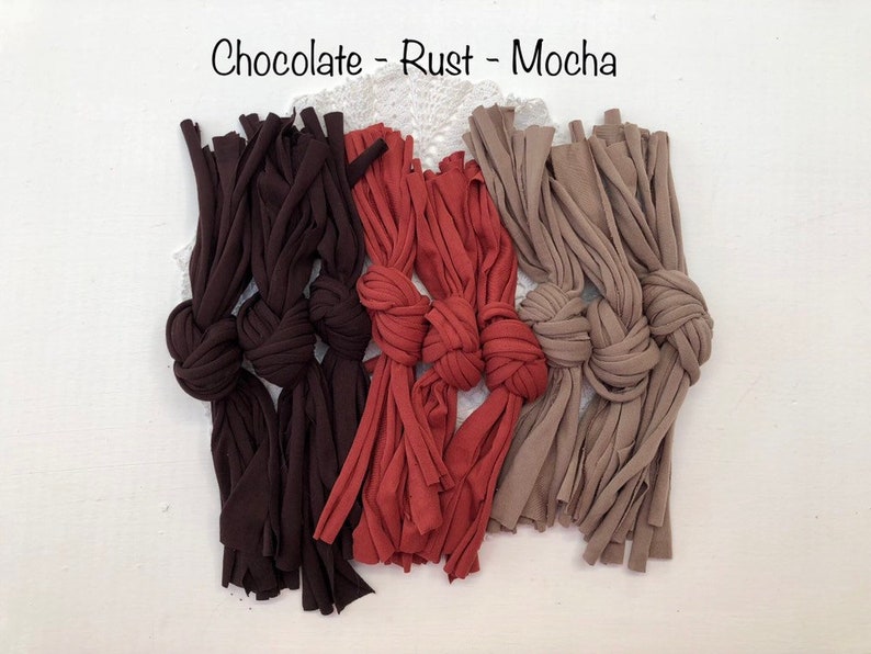 May include: Three knotted ropes in chocolate, rust, and mocha colors. The ropes are made of fabric and have frayed ends.