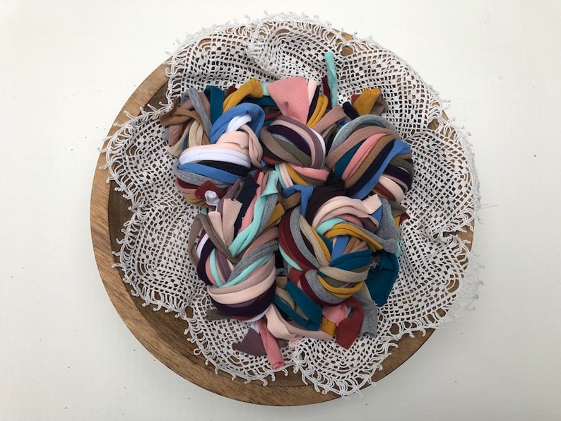 Puede incluir: Un cuenco de madera con un encaje blanco de ganchillo en su interior. El cuenco est&aacute; lleno de una variedad de retazos de tela de colores, incluyendo rosa, azul, verde, amarillo y marr&oacute;n.