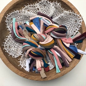 Puede incluir: Un bol lleno de diferentes trozos de tela de colores, incluyendo tonos de rosa, azul, verde, marr&oacute;n y amarillo. Los trozos de tela est&aacute;n dispuestos en una pila suelta y enredada.
