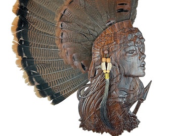 May include: A wooden carving of a woman's head with a turkey tail fan as a headdress. The carving is painted in shades of brown and features intricate details.