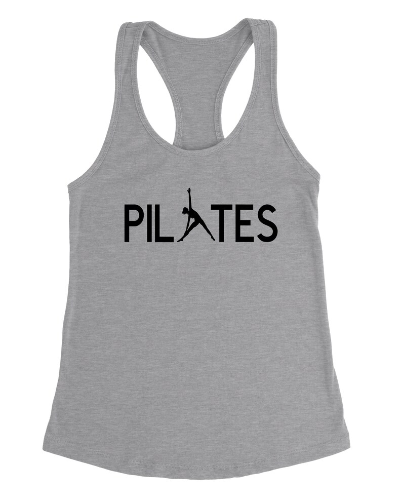 May include: A grey tank top with a black silhouette of a person doing a pilates pose and the word "PILATES" in black text.