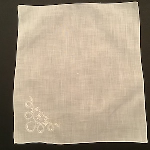 May include: A white cotton handkerchief with a delicate embroidered floral design in the corner.