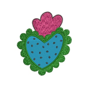 Könnte beinhalten: Ein gesticktes Herzdesign mit blauem Zentrum, das mit kleinen braunen Samen übersät ist, und einem grünen, gewellten Rand. Über dem Herzen befindet sich eine rosa, strukturierte Form. Das Design befindet sich auf weißem Hintergrund.