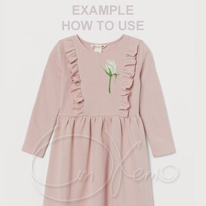 May include: A pink long-sleeved dress with a white rose embroidered on the front. The dress has ruffles on the shoulders and a flared skirt.