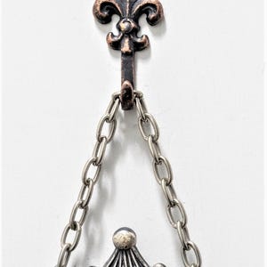Mini bronze fleur de lis hooks hanging a photo frame